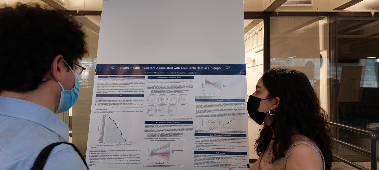 A student presenting a research poster to a professor