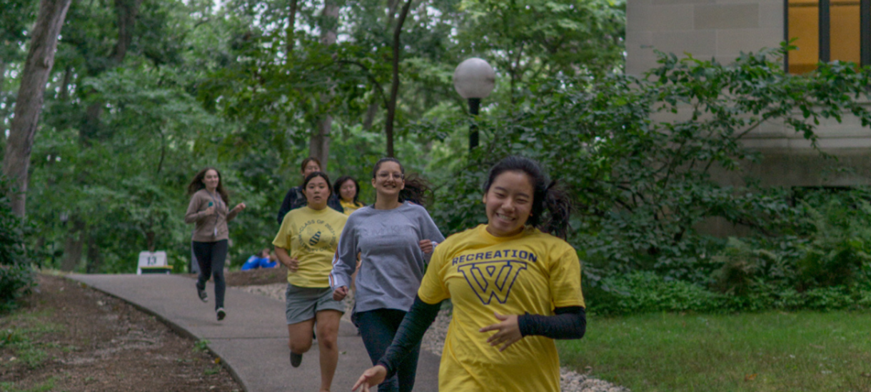students running in front of the library