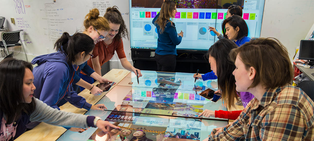 Students collaborating over a touchscreen table in the HCI lab