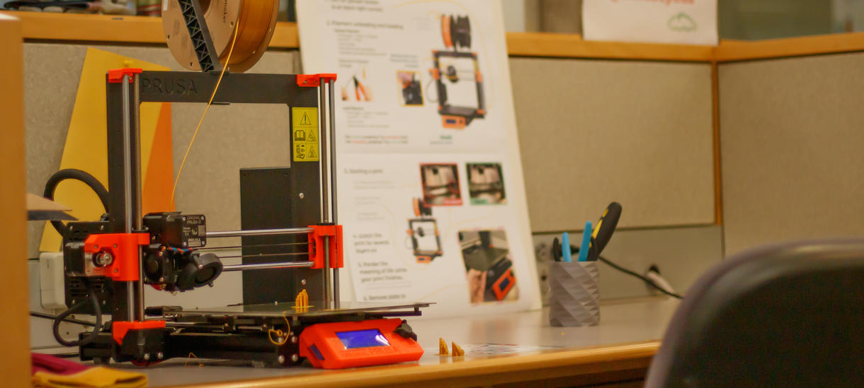 Knapp's Prusa 3D printer next to a printed out guide on how to use it.