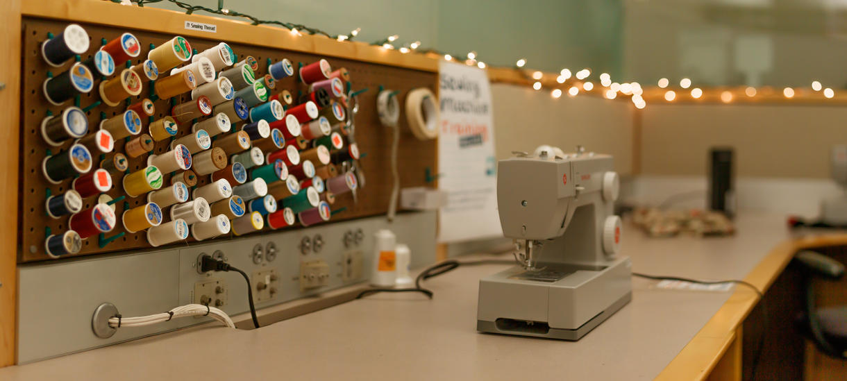 One of Knapp's Singer Heavy Duty sewing machine in front of pegboard of sewing thread