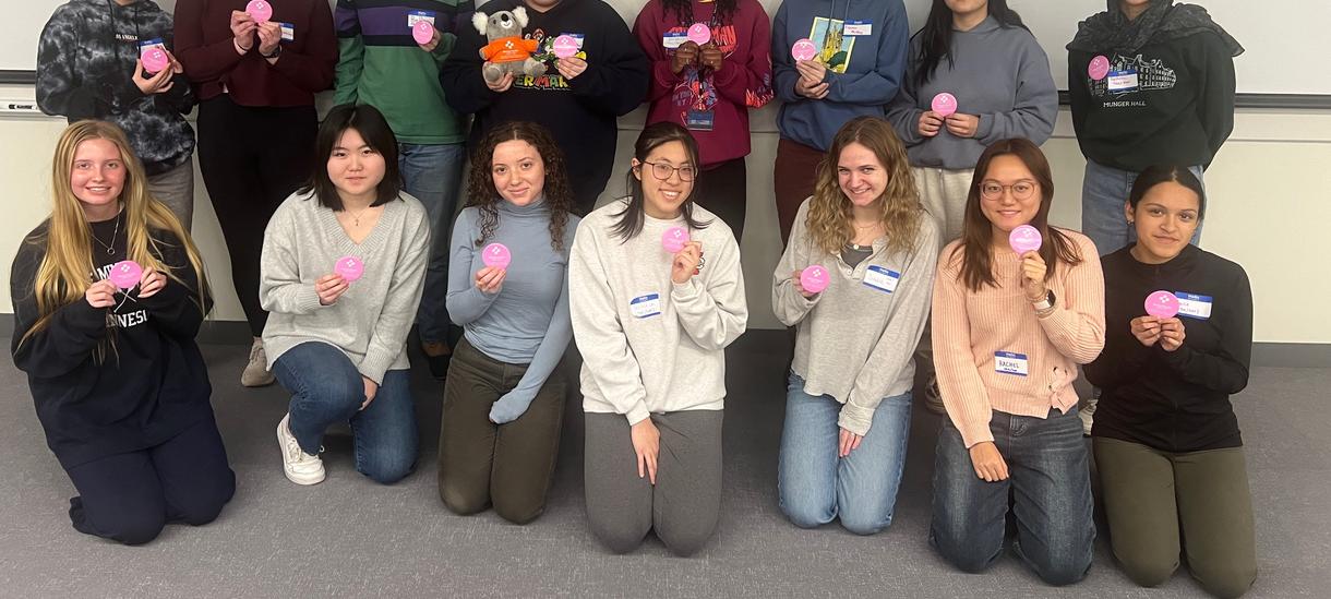 Group of students hold up pink pins that read "Mental Health First Aid"