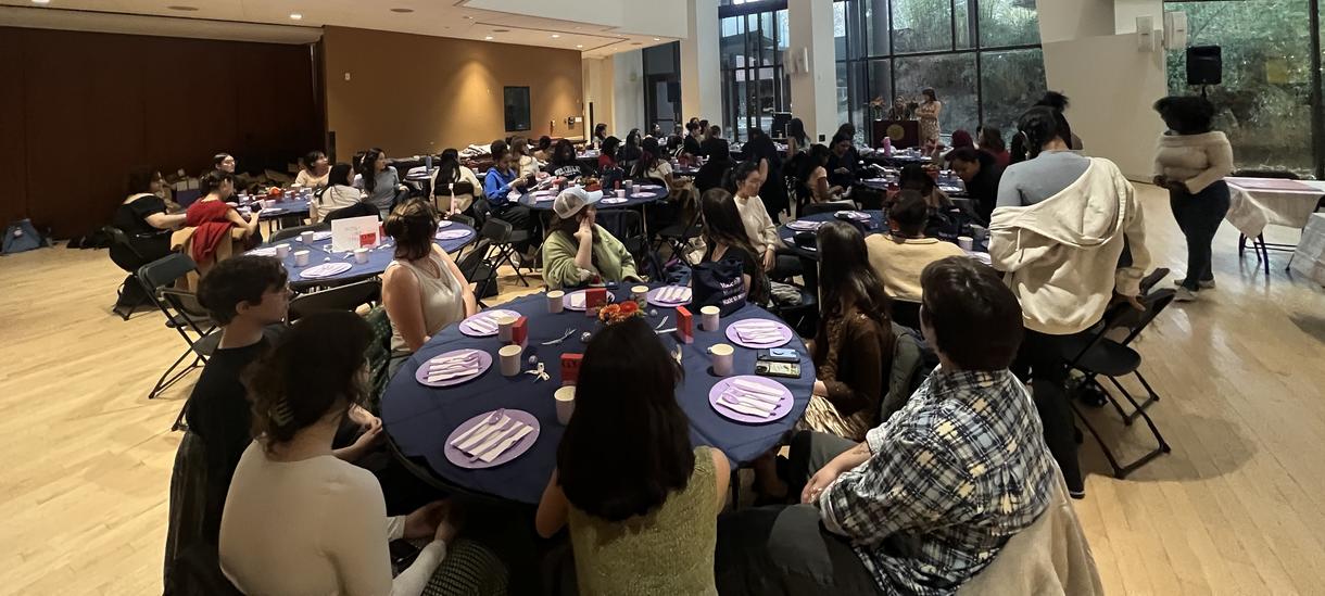 Students sit at tables sharing a meal