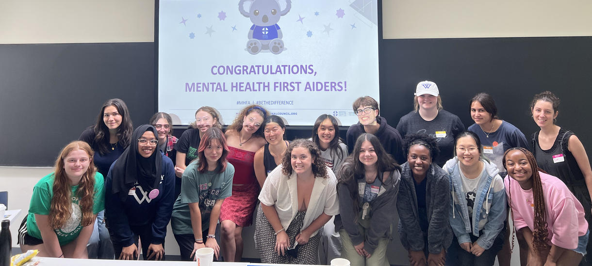 Group of students stand in front of screen that read "Congratulations Mental Health First Aiders"