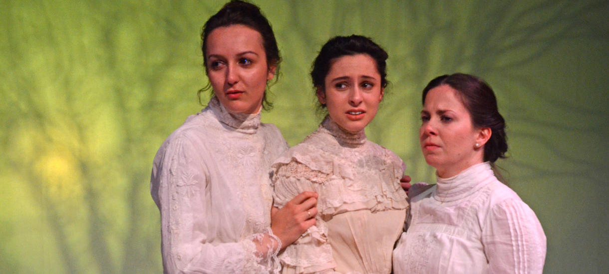 Three actresses in white 19th century dresses embracing against green backdrop
