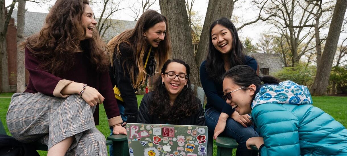 Students crowded around a laptop laughing