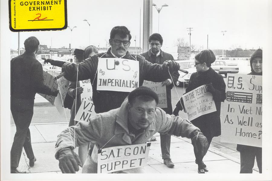 Protesters carry signs and act out "Saigon Puppet" demonstration in front of Wichita City Building.