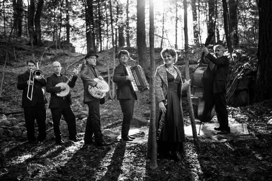 a black and white photo of the band Klezperanto standing in the forest