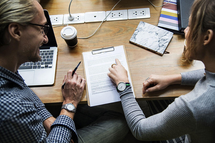 two people sitting at table discussing a typed research report
