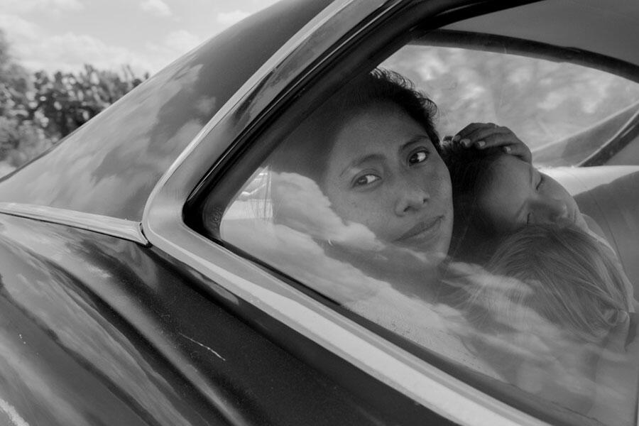 black and white image of a woman in car holding two children