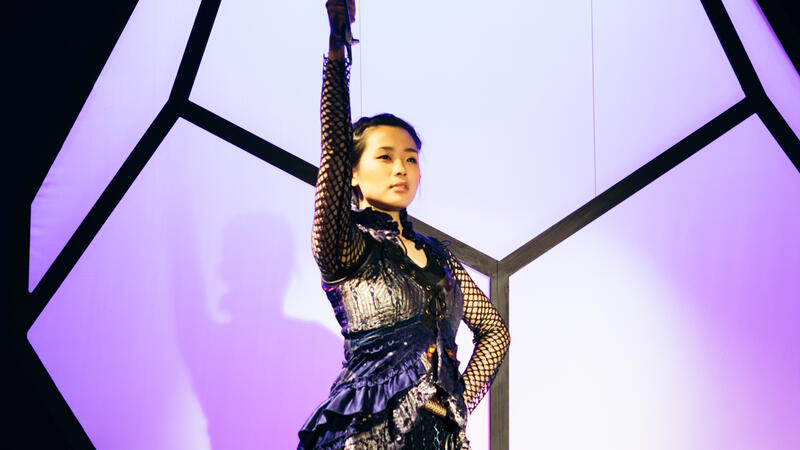 actor in purple dress raising sword