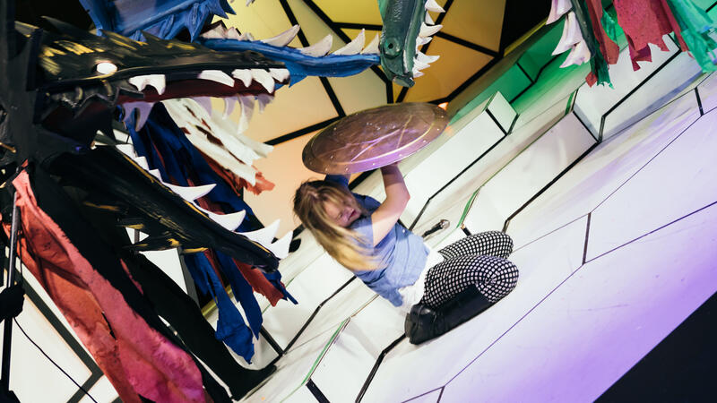 actor with shield cowering from dragon puppets