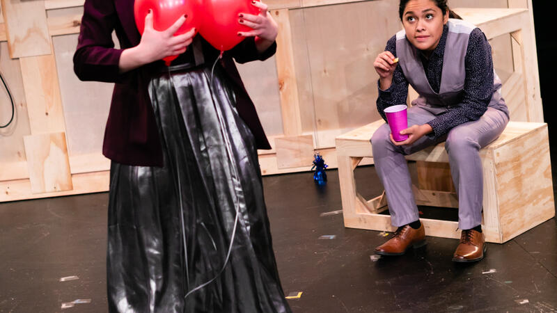 Actor with balloons held to chest, standing