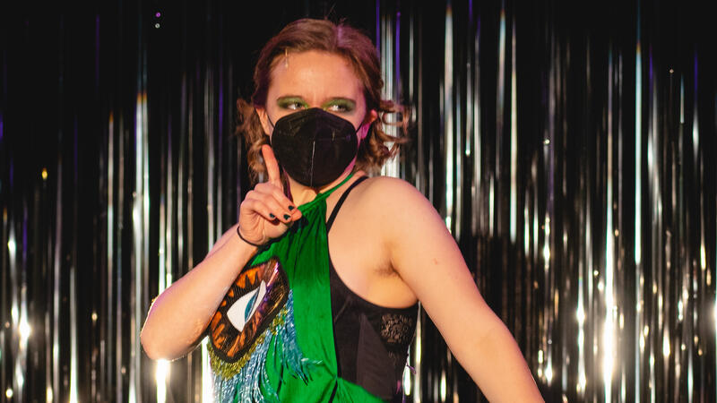 Cabaret dancer in front of glittery curtain.