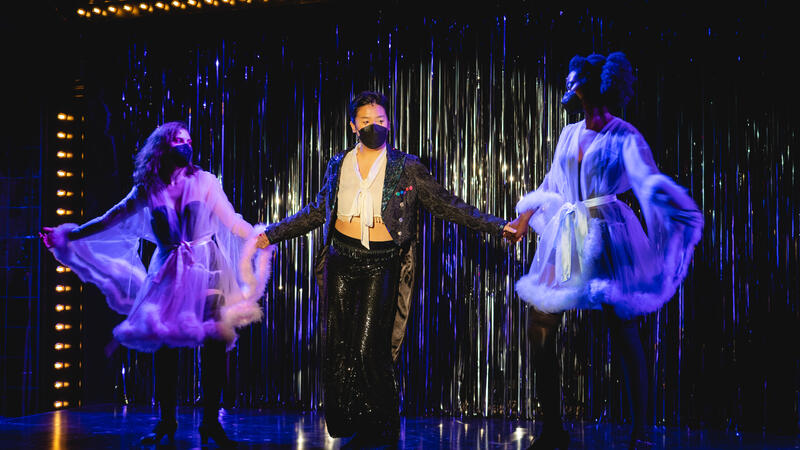 Emcee and two ladies dancing in front of curtain