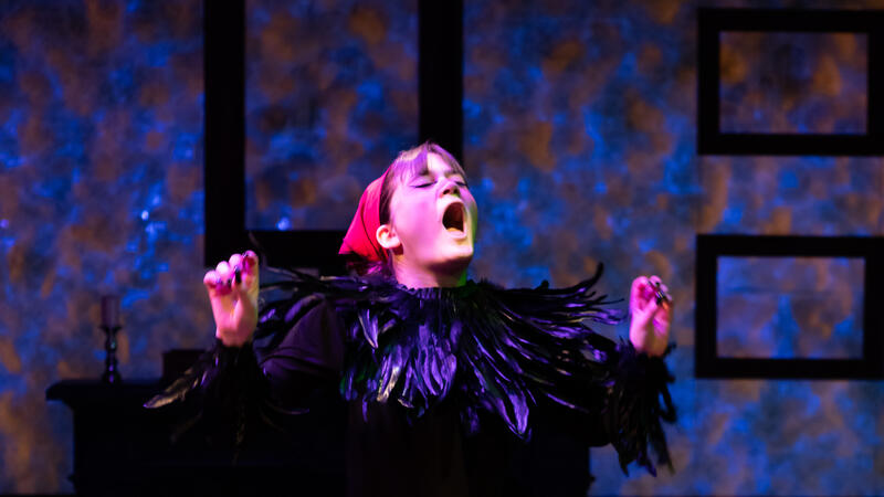 actor dressed as chicken with black feathers and red kerchief