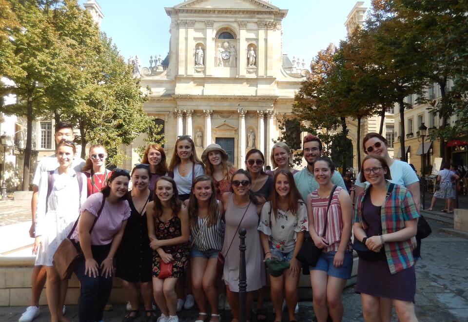 A photo of a group of Wellesley students smiling in France in a beautiful courtyard.