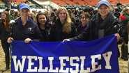 Equestrian team members hold a blue and white Wellesley Banner