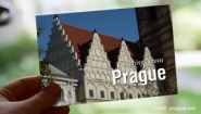 Hand holds a postcard that reads "Greetings from Prague"