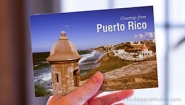 Hand holds a postcard that reads "Greetings from Puerto Rico"