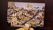 Hand holds a postcard that reads "greetings from San Francisco"