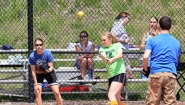 Fans look on from the stands as a softball player hits the ball