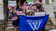 The Admission Office team holds signs welcoming newly-admitted students.