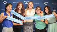 Final Hours of the 2016 Participation Challenge Alumnae hold "Wellesley Welcome" signs in front of a blue backdrop