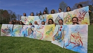 Students hold art from a calligraphy project exploring Arabic letters