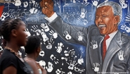 women walk in front of Mandela mural