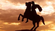 statue of Alexander the Great on rearing horse silhoetted against dramatic sunset