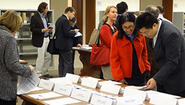 faculty chat and peruse colleagues' work laid out on tables in library