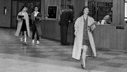 1959 photo of three students walking in library with coats on