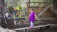 4 year old girl walks balance beam in playground