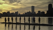 wellesley rowers stand in their shell on the Charles river, boston skyline in the background