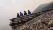 4 students watch sunset from dock on Lake Baikal