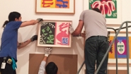 Two museum workers mount Matisse painting among others on wall