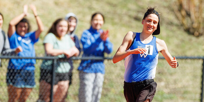 Ari Marks jogs around the new track at Wellesley and in the background spectators applaud.