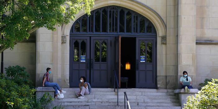 students socially distanced sitting on chapel steps