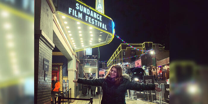 Claire Ayoub stands outside a Sundance sign with her arms outstretched.