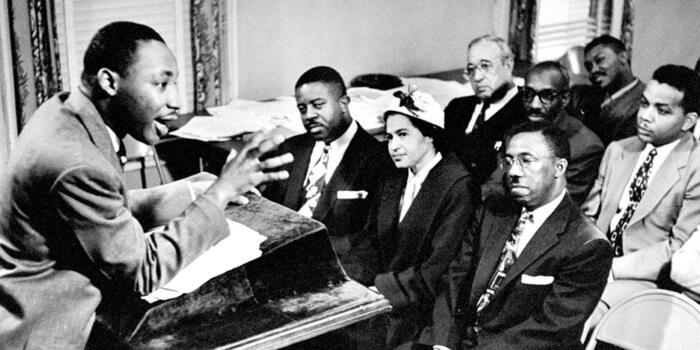 Martin Luther King talks to activists from a podium in a small room