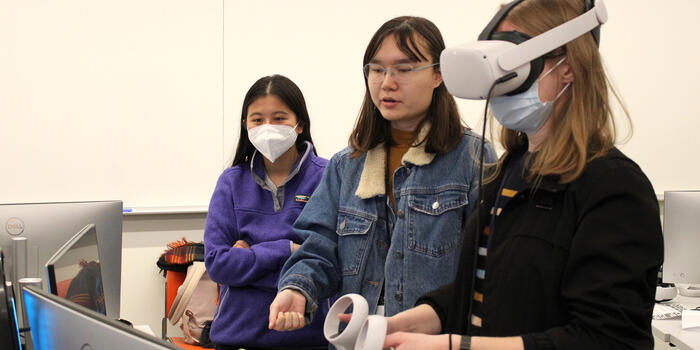 Rik Sampson ’23 (center) explains their virtual reality game to jury member Johanna Okerlund '14. 