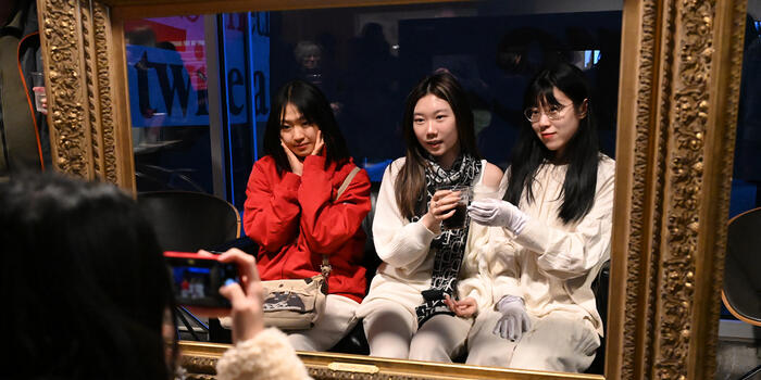 Three students pose for a photo within a gold frame.