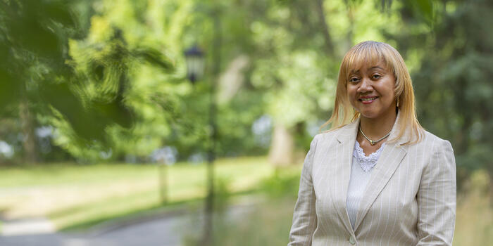 Jamie Motley smiles at the camera. Behind her is lush green campus.