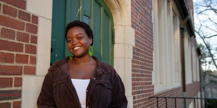 Kayla Bobb stands in front of a campus building and smiles at the camera.