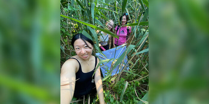 Two students and a professor pose for a photos in a stand of phragmites reeds.