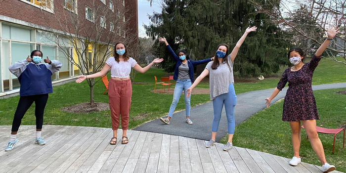 people wearing masks and posing with their hands up in the air