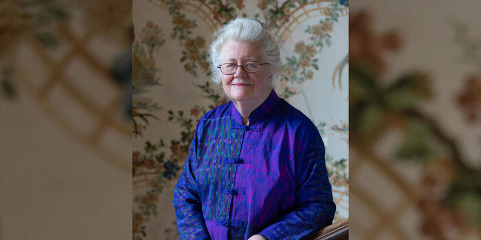 Peggy McIntosh on Cheever House’s grand staircase with original wallpaper and bannister dating from 1894.