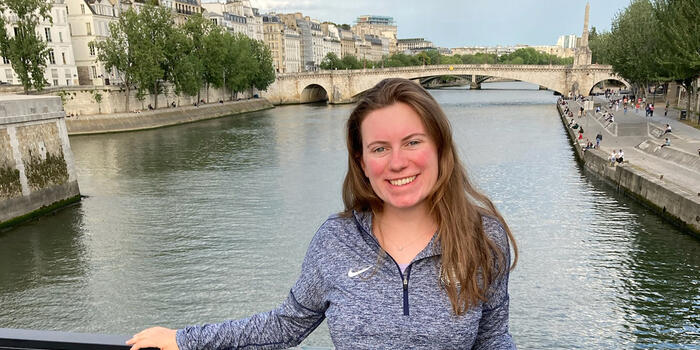 Rosalind Lucier ’22 stands in front of a channel of water with historic buildings behind her.