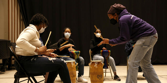 Kera Washington demonstrates drumming to students in Yanvalou.